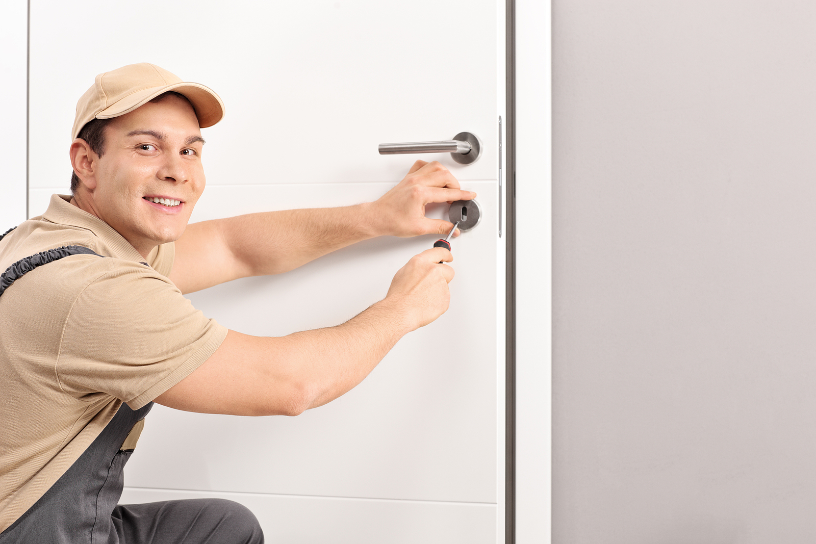 Cheerful Locksmith Installing A Door Lock On A New White Door An Cheerful Locksmith Installing A Door Lock On A New White Door An