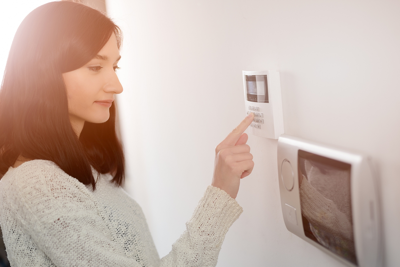 A woman using a wall-mounted smart lock keypad in her home, showcasing modern security solutions for residential properties in Thornhill. A woman using a wall-mounted smart lock keypad in her home, showcasing modern security solutions for residential properties in Thornhill.
